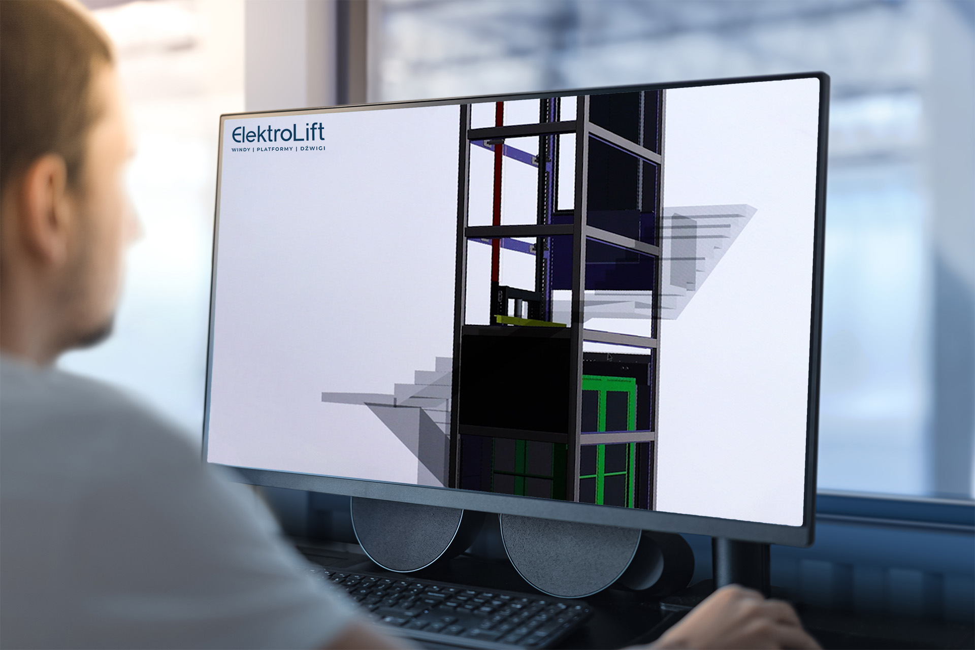 Osoba pracująca przy monitorze na którym wyświetlony jest projekt windy i logo elektrolift